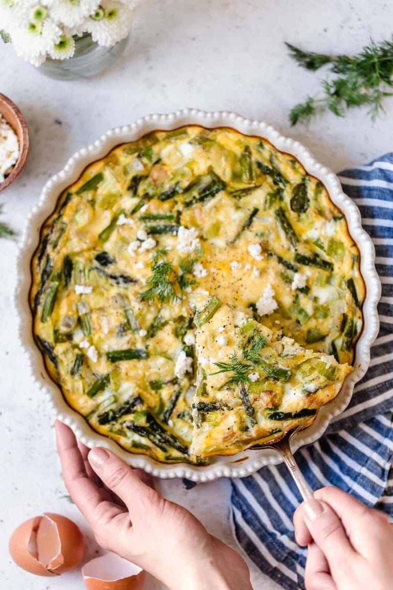 Overhead view of crustless asparagus, leek and feta quiche topped with feta cheese and fresh dill. 