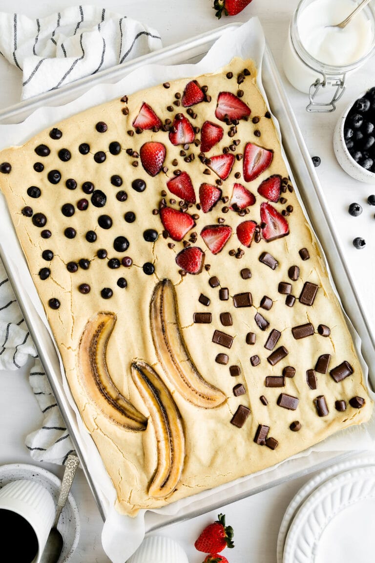 Overhead view of easy sheet pan pancakes topped with fresh fruit and chocolate chunks. 