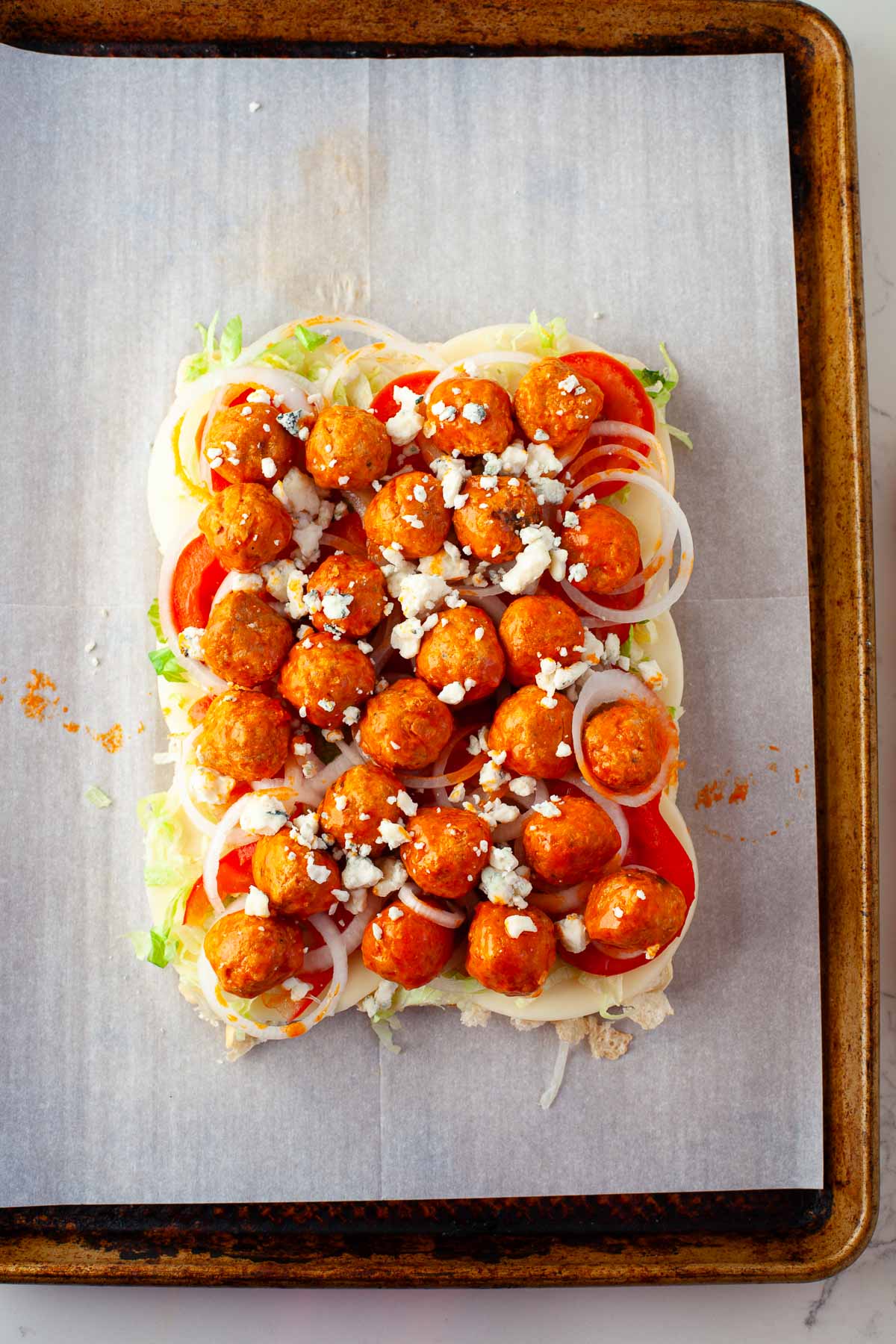 buffalo chicken meatball sliders layered with provolone, tomato, lettuce, onion, crumbled blue cheese