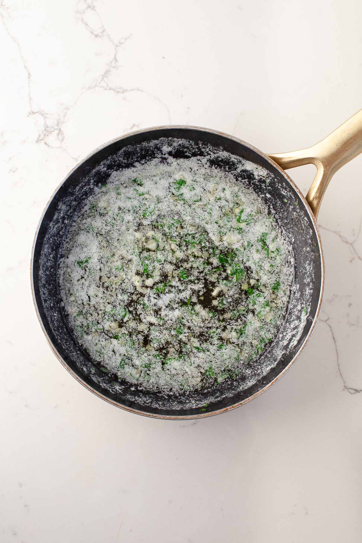 garlic parsley infused melted butter in small black sauce pan on marble surface