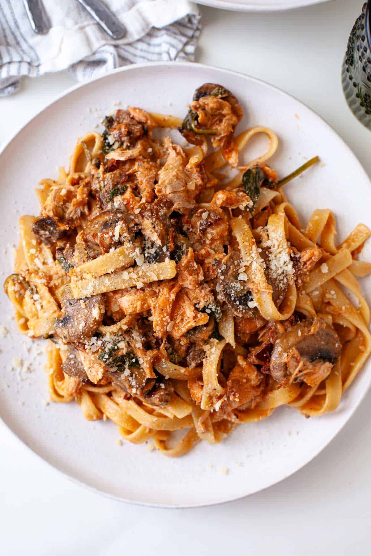 pasta with blackened salmon, mushrooms, and spinach covered in sun-dried tomato sauce