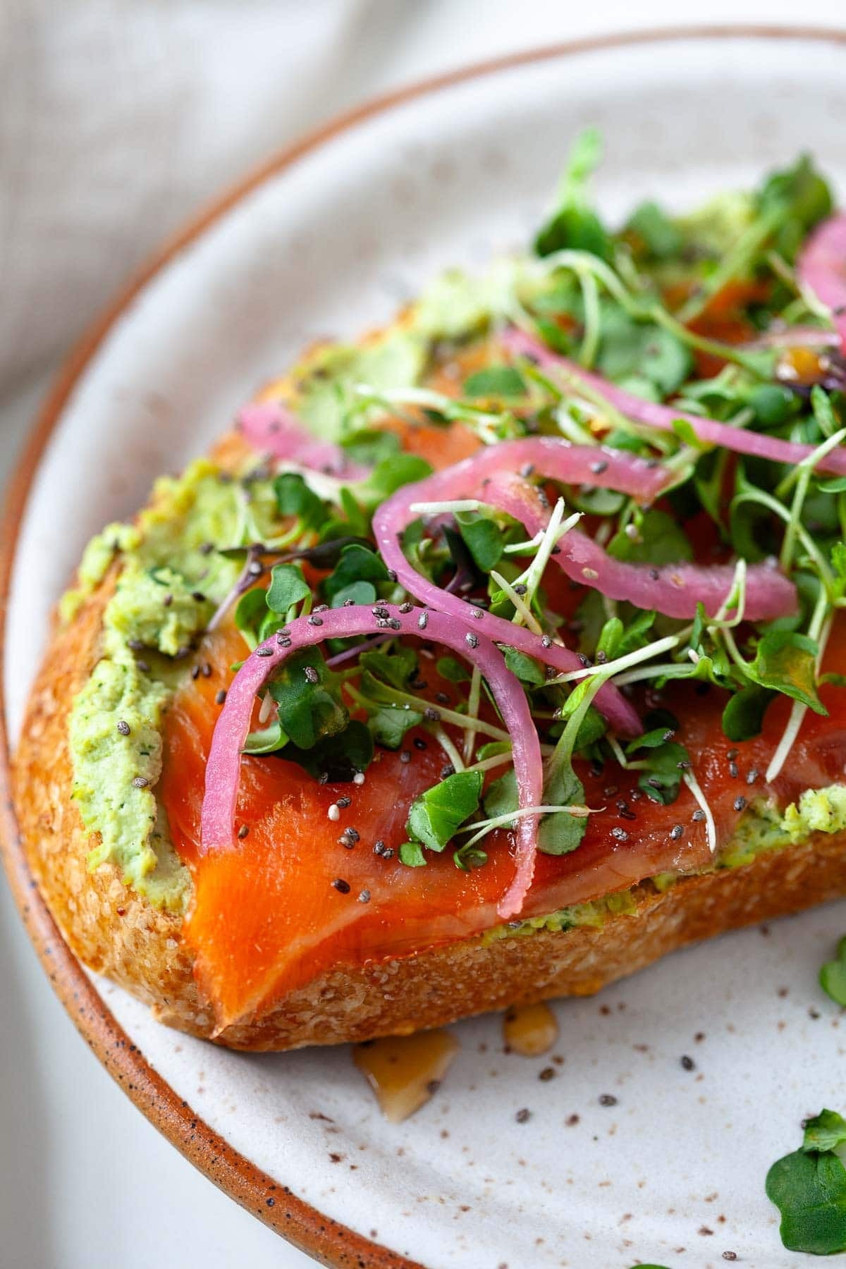 toast with smashed edamame, smoked salmon, microgreens, and pickled red onion